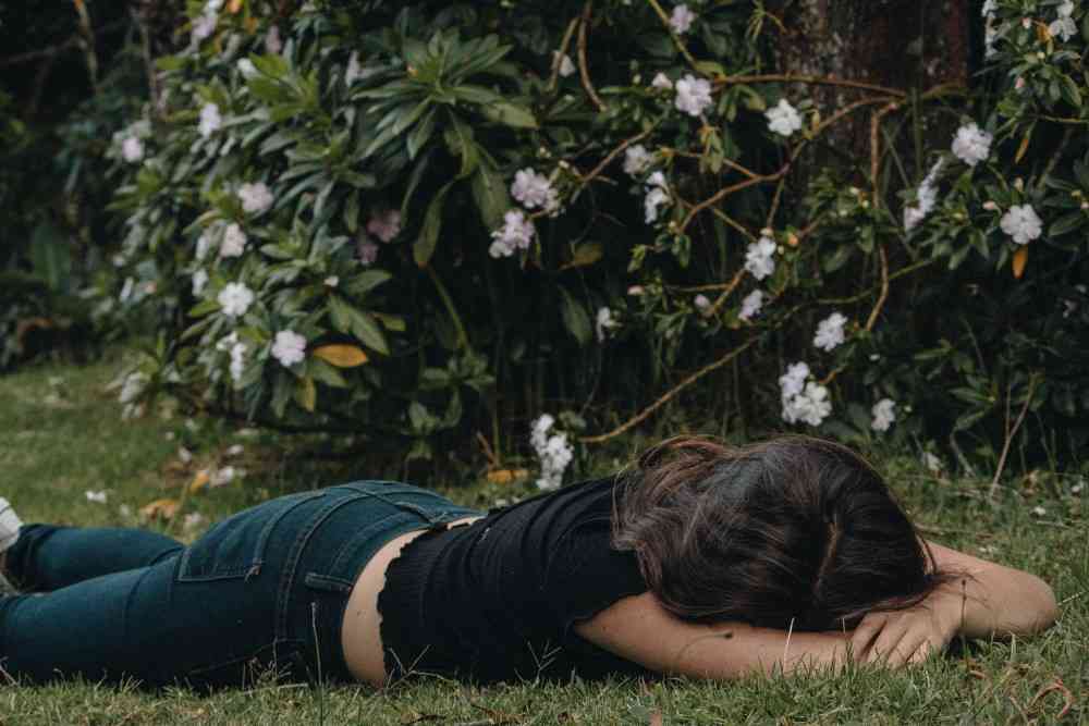 Présentation d'une femme épuisée allongée dans l'herbe pour syringomyélie et fatigue