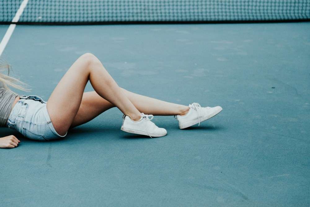 Femme ayant douleur musculaire aux jambes pendant son tennis