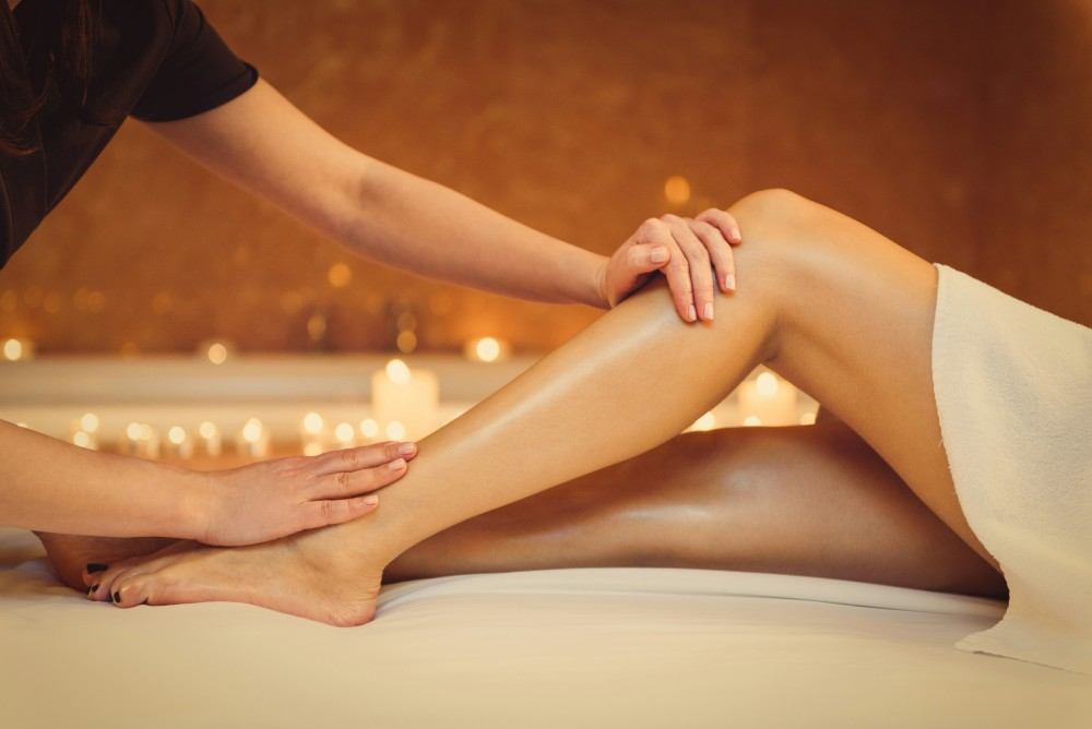 Femme se faisant masser les jambes pour soulager ses douleurs musculaires