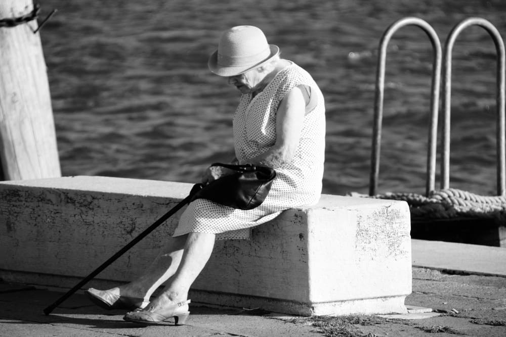 Dame au chapeau assise avec sa canne, perte de force musculaire