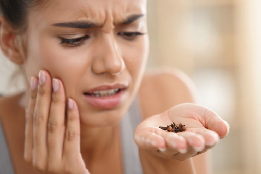 Femme ayant mal aux dents et clous de girofle dans la main