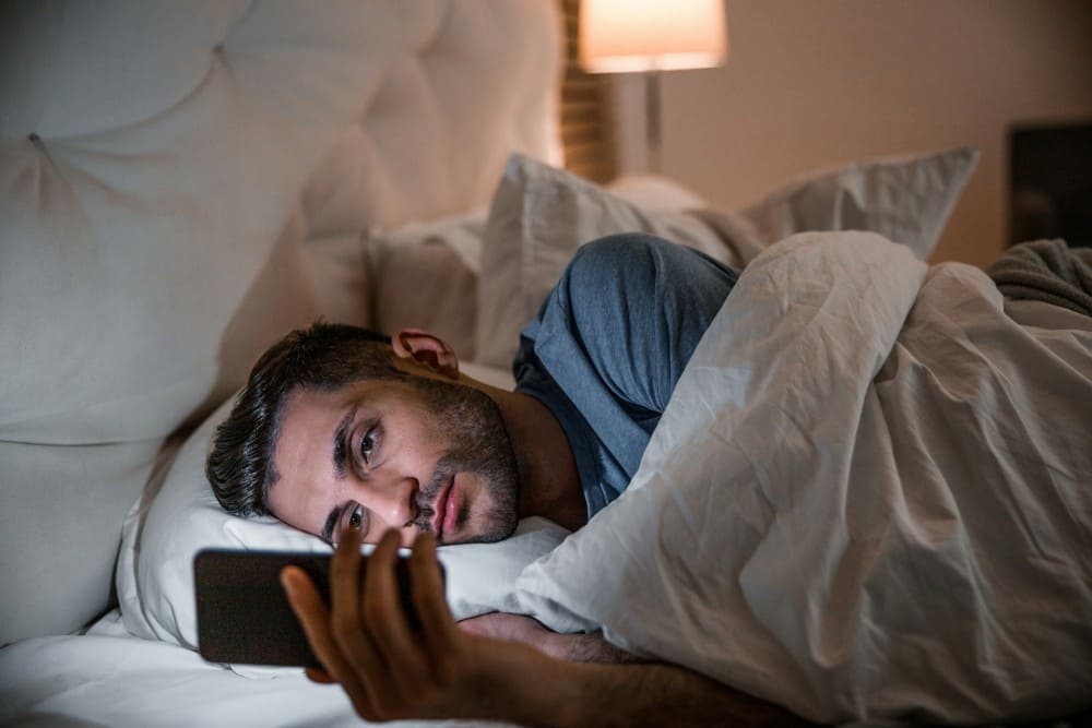 Homme qui regarde son portable dans son lit