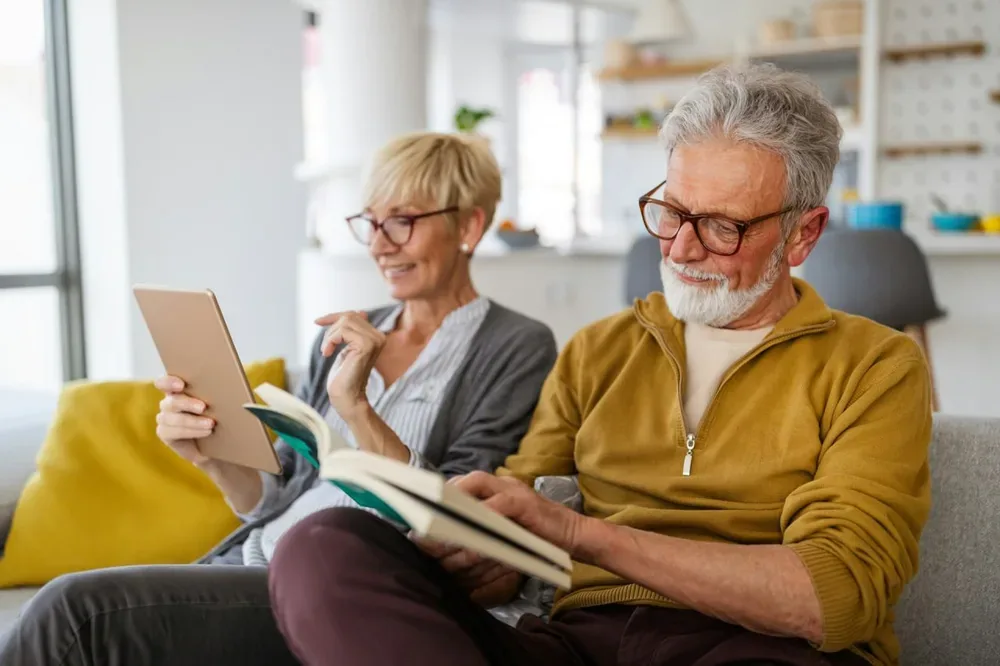 Couple de seniors lisant et échangeant à la maison