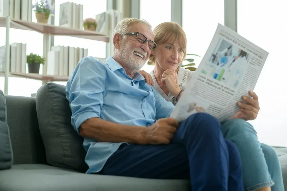 Couple de seniors lisant le journal dans leur salon
