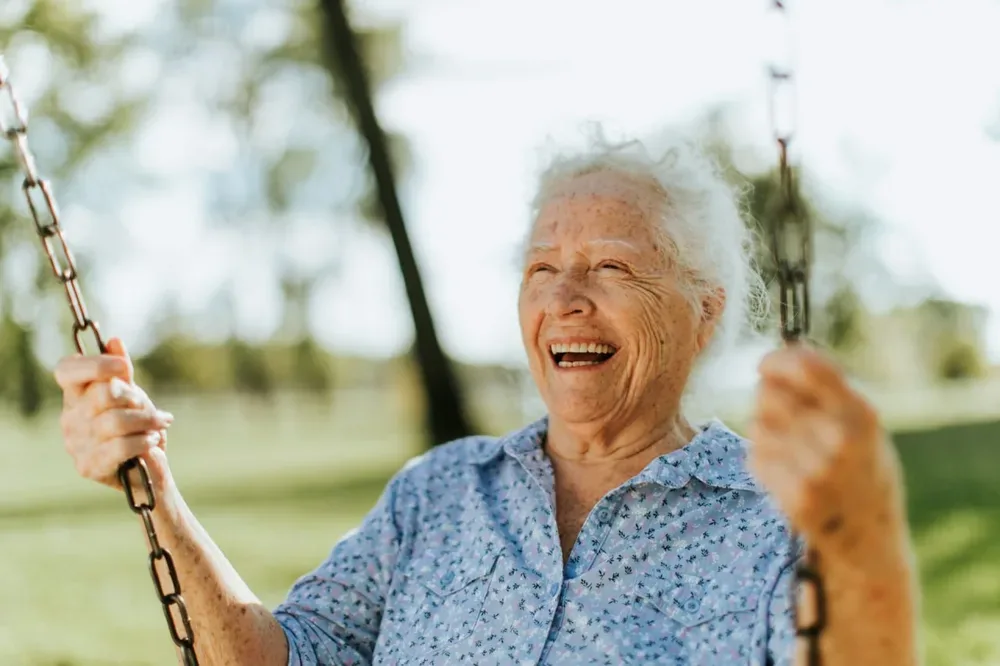 Femme âgée souriante sur une balançoire dans un parc