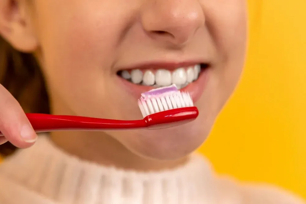 Fille se brossant les dents avec une brosse à dents rouge et blanche