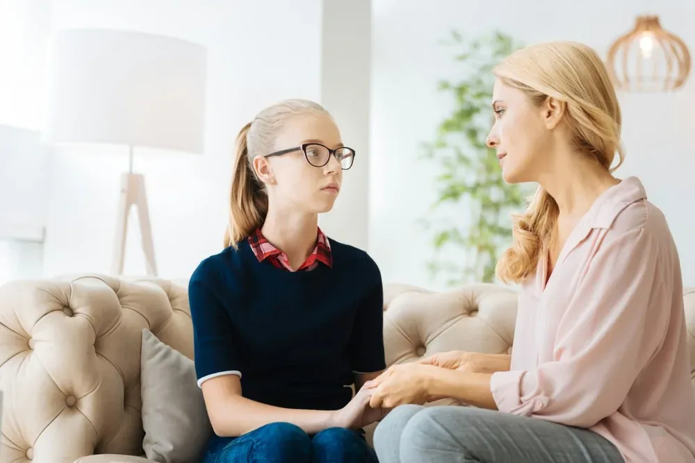 Une fille tient les mains de sa mère assise près d elle dans une scène familiale évoquant la prosopagnosie