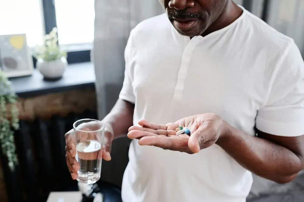 Lyrica : un homme tient des médicaments et un verre d’eau avant sa prise quotidienne.